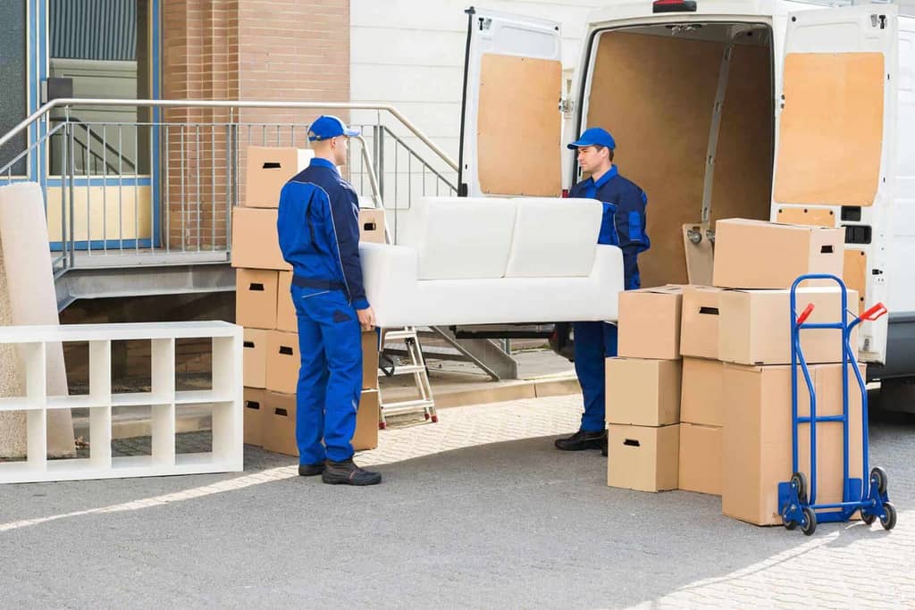 Furniture delivery crew bringing a boxed piece in from the truck