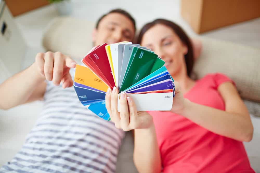 Homeowner testing paint swatches on foam boards to find the perfect home decor color palette under different lighting conditions.