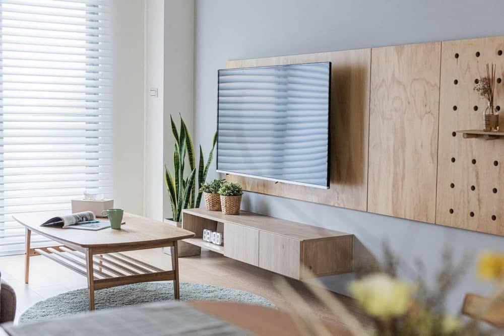 DIY TV stand combining wood, glass, and metal beside a Mario Bellini sofa, showcasing layered modern design.