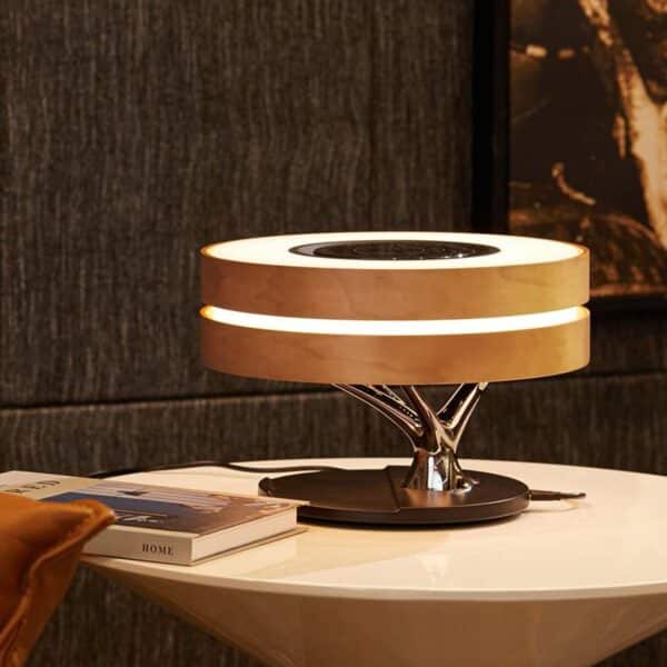 Stylish Circle of Life® Lamp with an integrated wireless charging pad, showcasing its sleek design and warm light on a wooden bedside table.