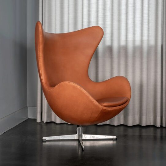 An Egg Chair Replica showcasing its sleek design, cocoon-like shape, and luxurious leather upholstery, set against a minimalist backdrop.