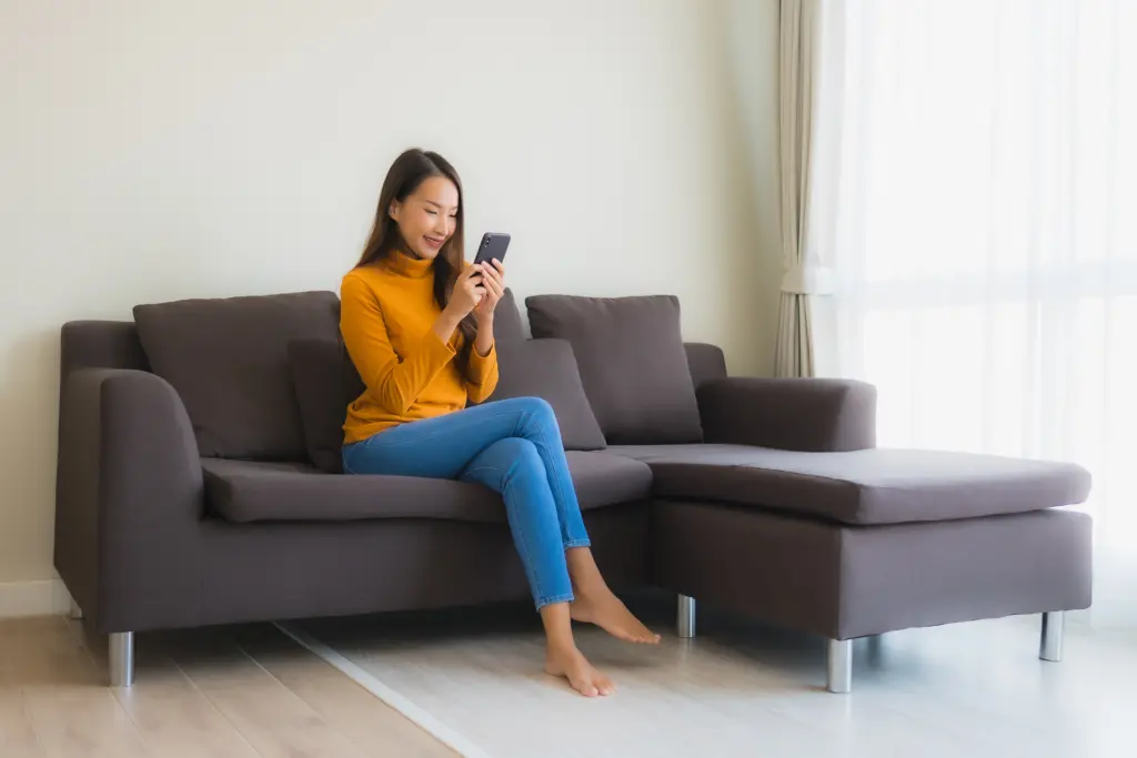 portrait young asian woman using smart mobile phone sofa with pillow living room - Living Space Sofa