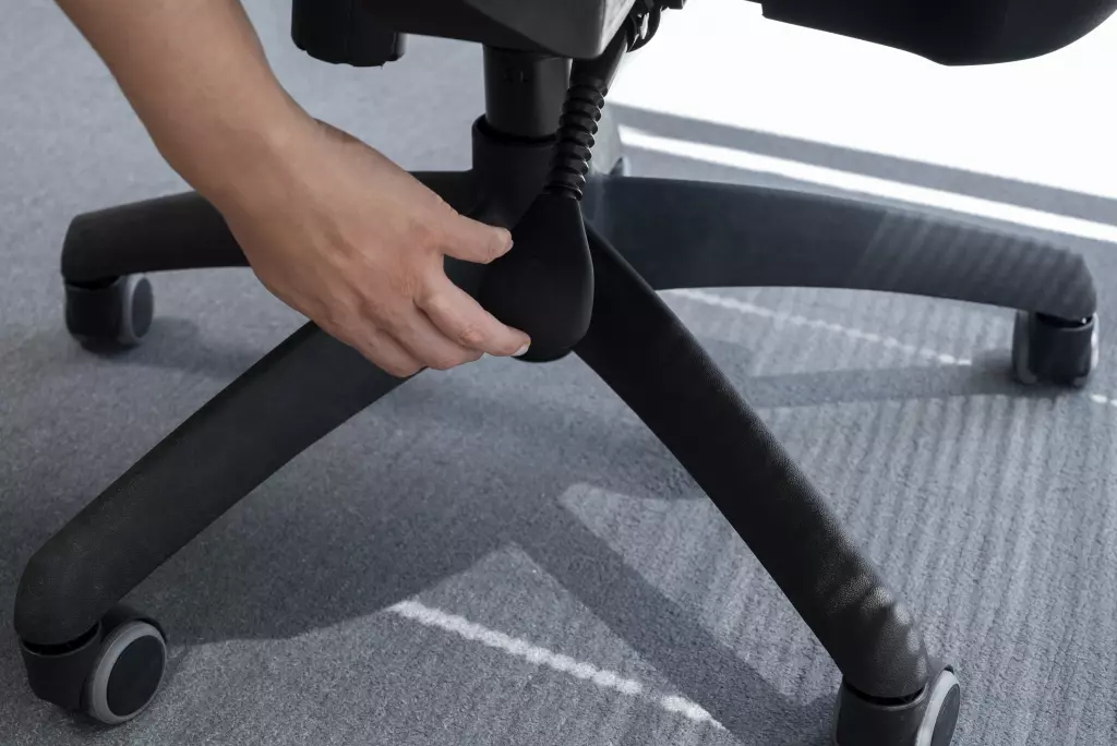 Close-Up Of A Person's Hand Adjusting The Height Lever Under An Office Chair.