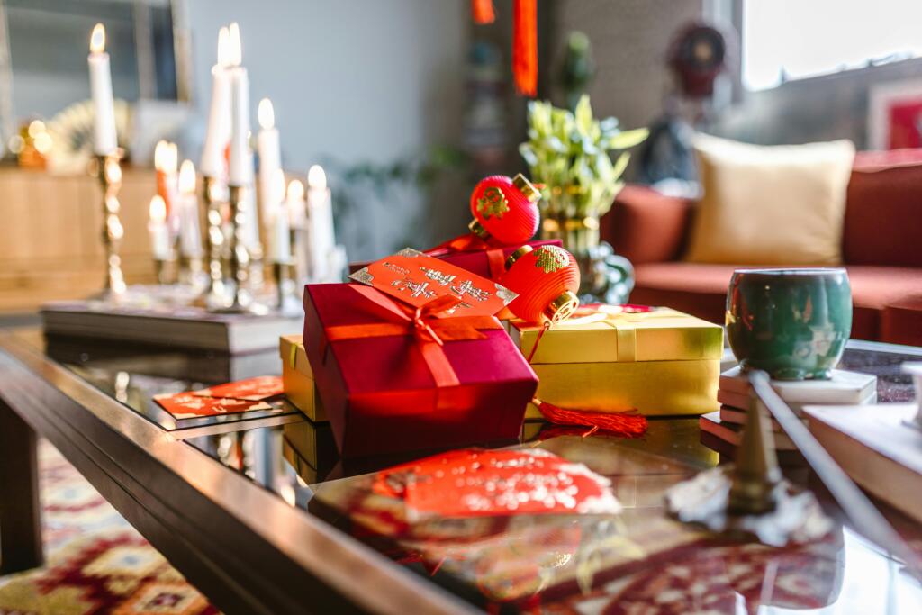 A beautifully decorated living room table set for Chinese New Year celebrations, featuring candles and red gifts.