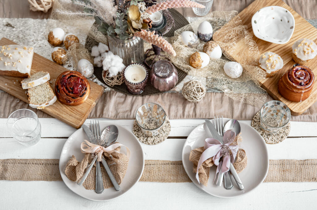 A festive table with beautiful dishes, decorative items and pastries. Easter table setup design idea.