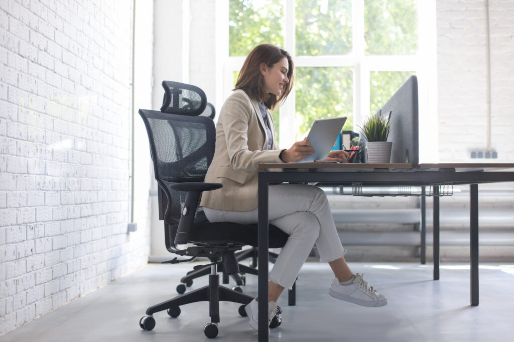 beautiful caucasian business woman is working using digital tablet while sitting creative office | Sohnne® tips to prevent sciatica