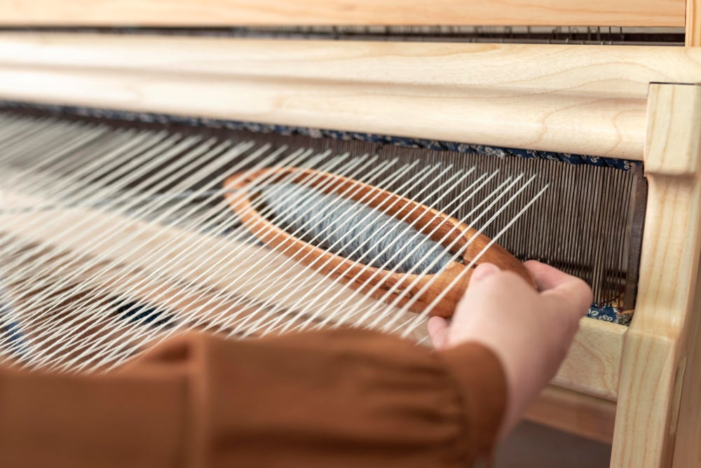 person weaving yarn