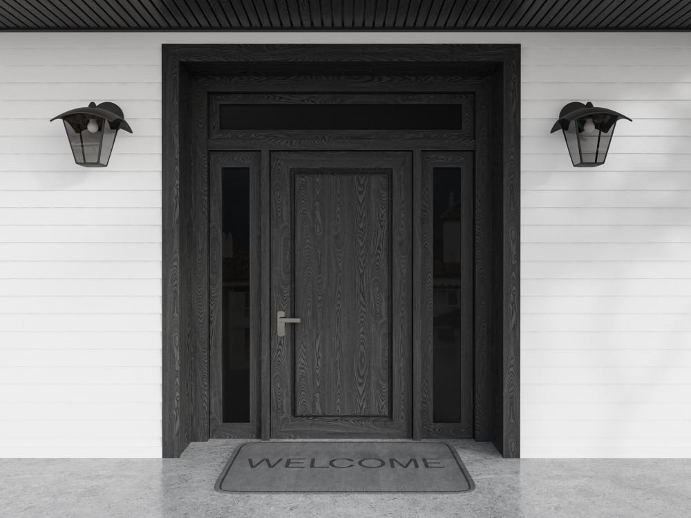 Front door of black and white wooden house with welcome mat entrance