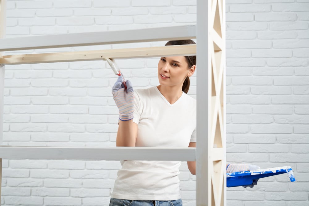 8786 | Sohnne® Woman repainting a wooden shelf as part of decorating apartment on a budget.