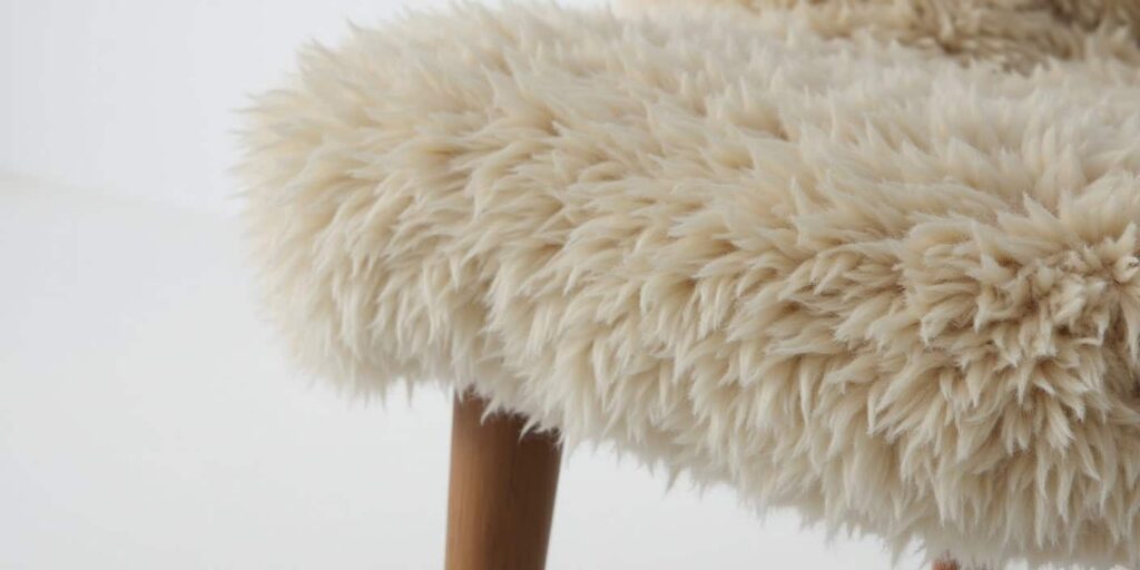 Close-up of Scandinavian sheepskin upholstery showing soft wool texture and craftsmanship in a clean, modern setting.