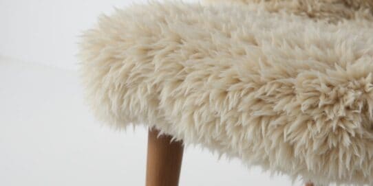 Close-up of Scandinavian sheepskin upholstery showing soft wool texture and craftsmanship in a clean, modern setting.